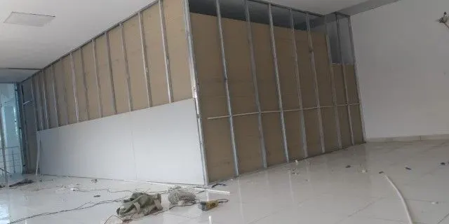 Gypsum partition wall part-boarded over its metal stud frame in an empty hall Gypsum partition wall part-boarded over its metal stud frame in an empty hall