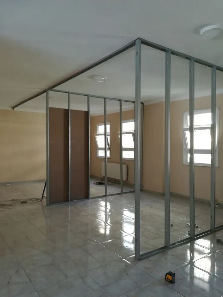 Metal stud frame for a room partition, with gypsum boards going up alongside