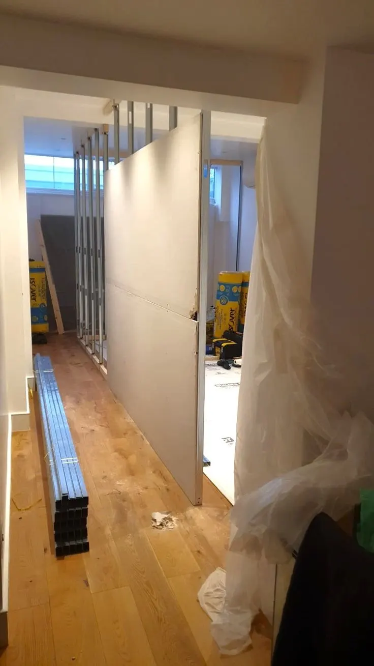 Gypsum partition boards being fitted along a narrow corridor Gypsum partition boards being fitted along a narrow corridor